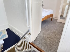 Ein Schlafzimmer mit einem hölzernen Bett, einer weißen Tür, einem dunkelblauen Teppich und einer weißen Wand mit einer Karte.