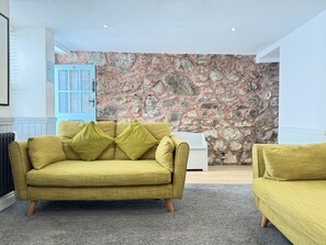 Ein Zimmer mit einer Steinwand, einem gelben Sofa und einer blauen Tür.