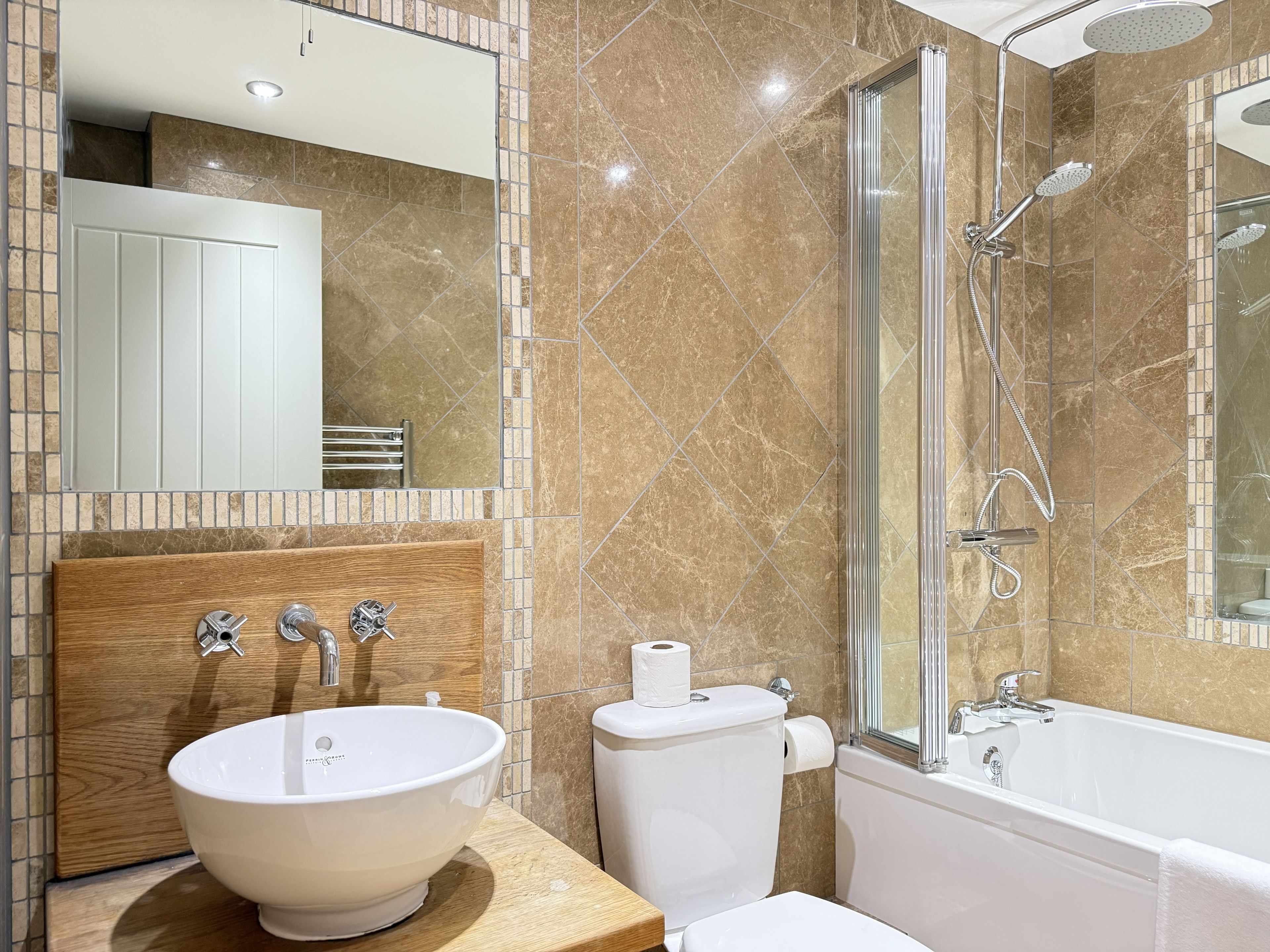 Un baño moderno con un lavamanos blanco grande, un inodoro, una bañera y una ducha con mampara de vidrio.
