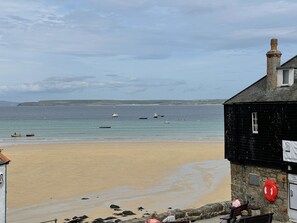 Une plage avec des bateaux sur l’eau, un rivage sablonneux et un bâtiment portant une enseigne.