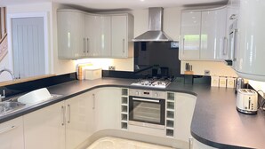 A modern kitchen with white cabinets, a built-in oven, and a gas stove. - Harrys Hideout - a cottage that sleeps 4 guests in 2 bedrooms (St Ives)