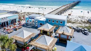 Ein Strandhotel mit Steg, Strand und Hütten mit Reetdach.