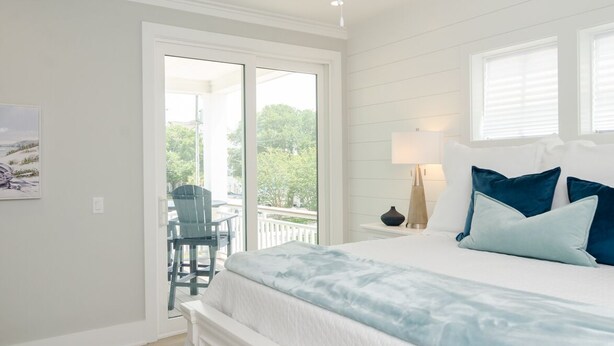 Une chambre avec un grand lit, une table de chevet, une chaise et une vue sur un balcon.