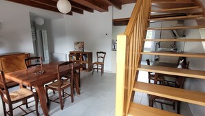 A dining area with wooden furniture, a staircase, and a view of the kitchen. - Gîte de la Basse Roche (Souge)