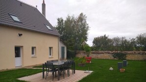 A house with a patio area featuring a table and chairs. - Gîte de la Basse Roche (Souge)