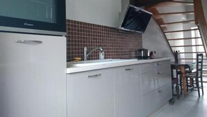 A kitchen with a built-in oven, a microwave, and a tiled backsplash. - Gîte de la Basse Roche (Souge)
