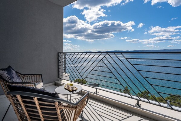 A balcony with wicker furniture, a small round table with a tray, and a view of the sea.