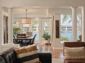 A dining area with a view of a body of water, a large potted plant, and a hanging light fixture. - Waterfront Oasis - King Beds • 10min Walk to Beach (Cocoa Beach)