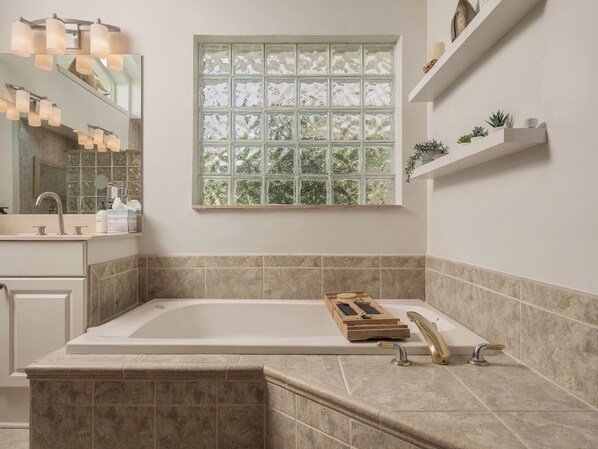 A modern bathroom with a freestanding bathtub, a large mirror, and a window with a view of trees.