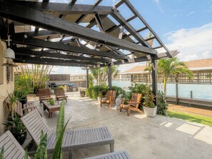 Une terrasse extérieure couverte, aménagée avec des sièges et offrant une vue sur une piscine.