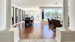 A spacious room with a wooden floor, large windows, and a view of the outdoors. - Waterfront Oasis - King Beds • 10min Walk to Beach (Cocoa Beach)