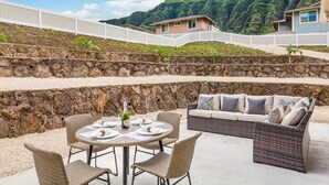 Un espace extérieur aménagé avec un mur en pierre, une table ronde et un canapé avec des coussins.