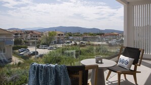 A balcony with a view of a parking lot and distant mountains. - Achillion Suites (Lefkada)