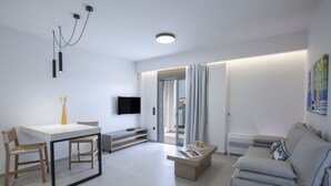 A modern living room with a white sofa, a coffee table, and a dining area with a white table and chairs. - Achillion Suites (Lefkada)