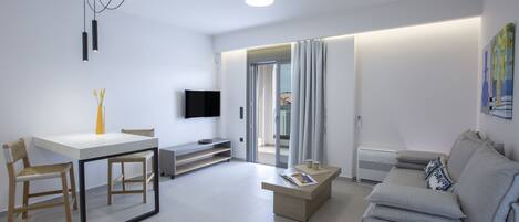 A modern living room with a white sofa, a coffee table, and a dining area with a white table and chairs.