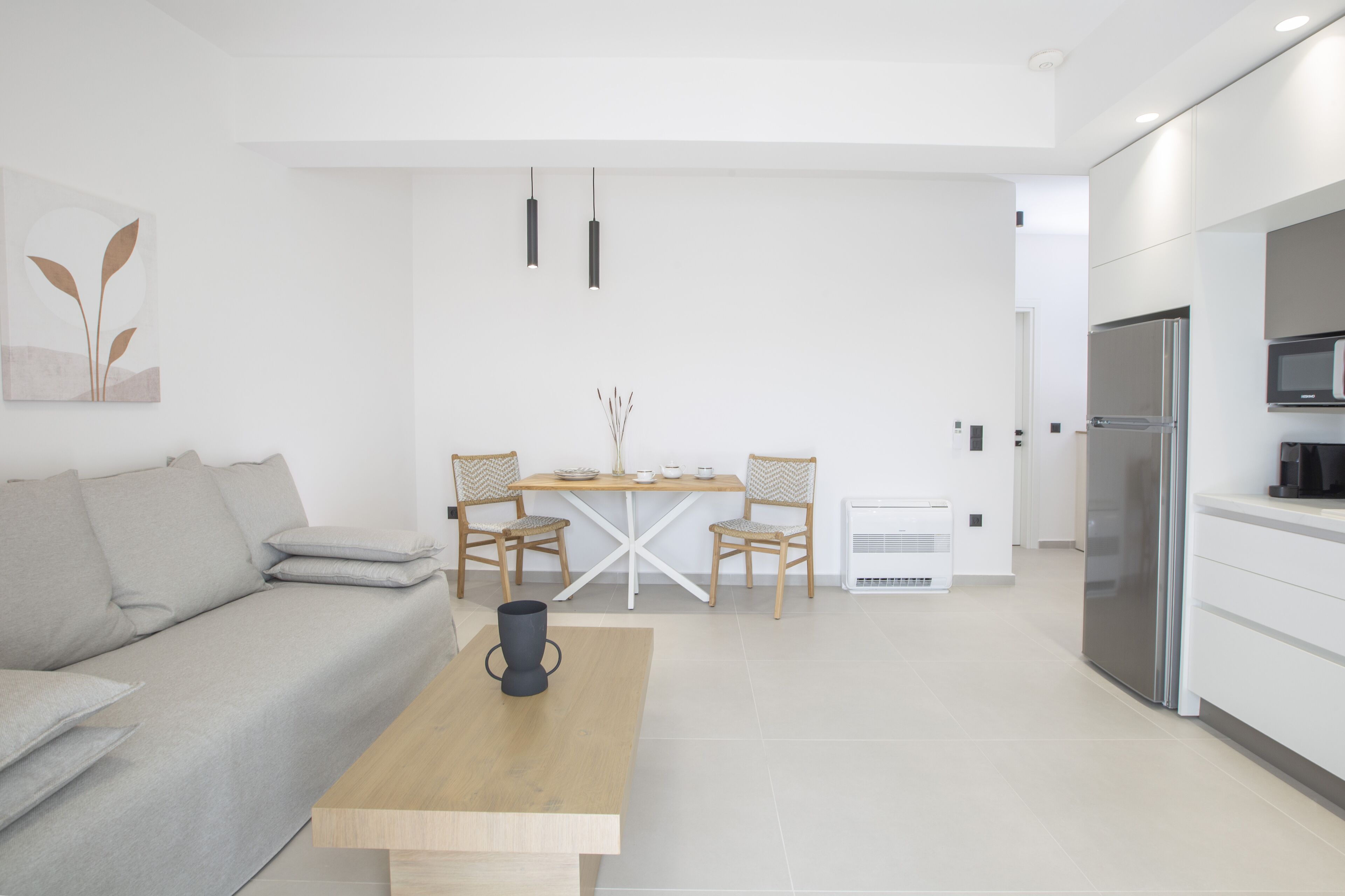 Una cocina moderna con refrigerador integrado, un comedor con mesa y sillas de madera, y un sofá con cojines.