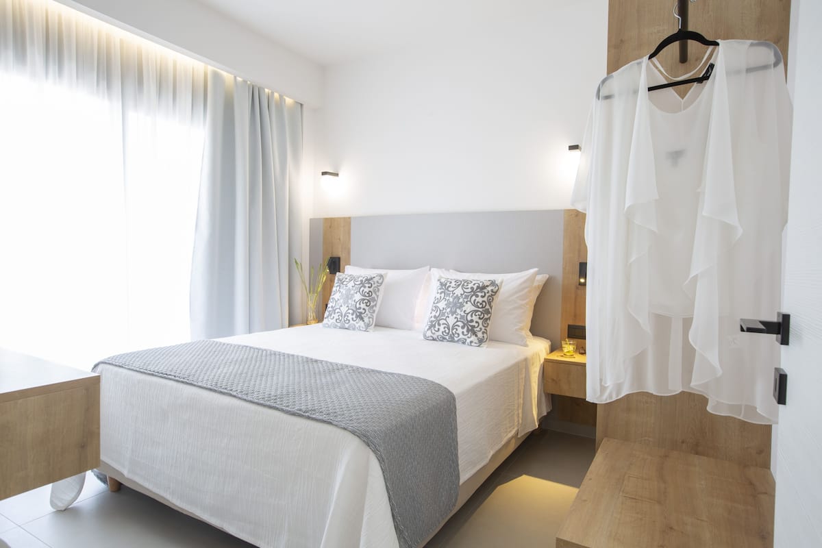 A modern bedroom with a large bed, bedside tables, a hanging light, and a view of the outdoors.