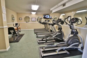 Ein Fitnessstudio mit Laufbändern, Crosstrainern und Fahrrädern.