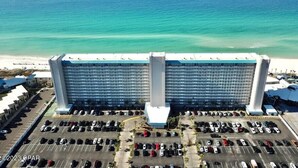 Un grand hôtel avec un parking situé devant, offrant une vue sur une plage et l’océan.