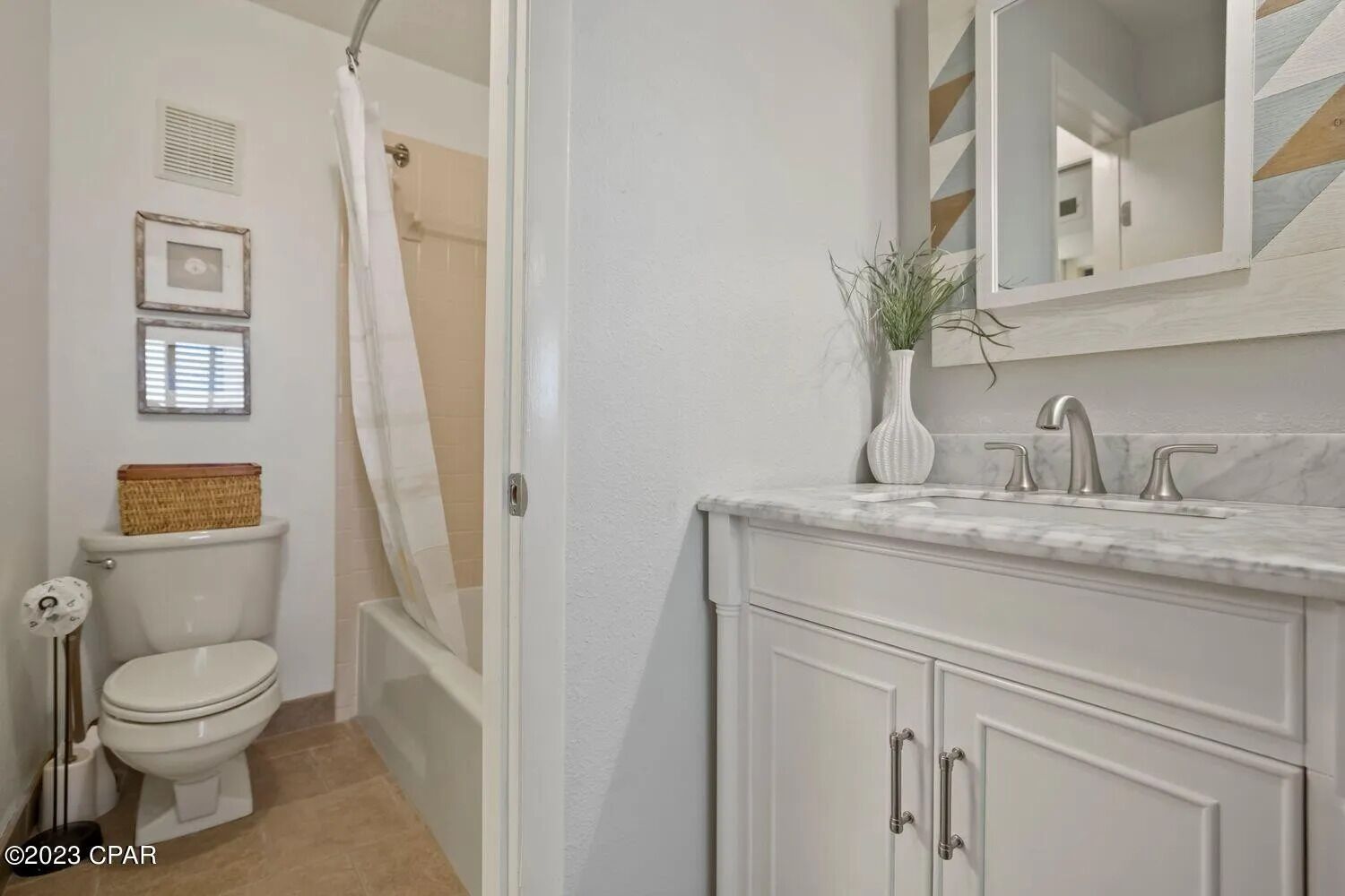Une salle de bain comprenant des toilettes, une douche, un meuble-lavabo avec un miroir et une plante.
