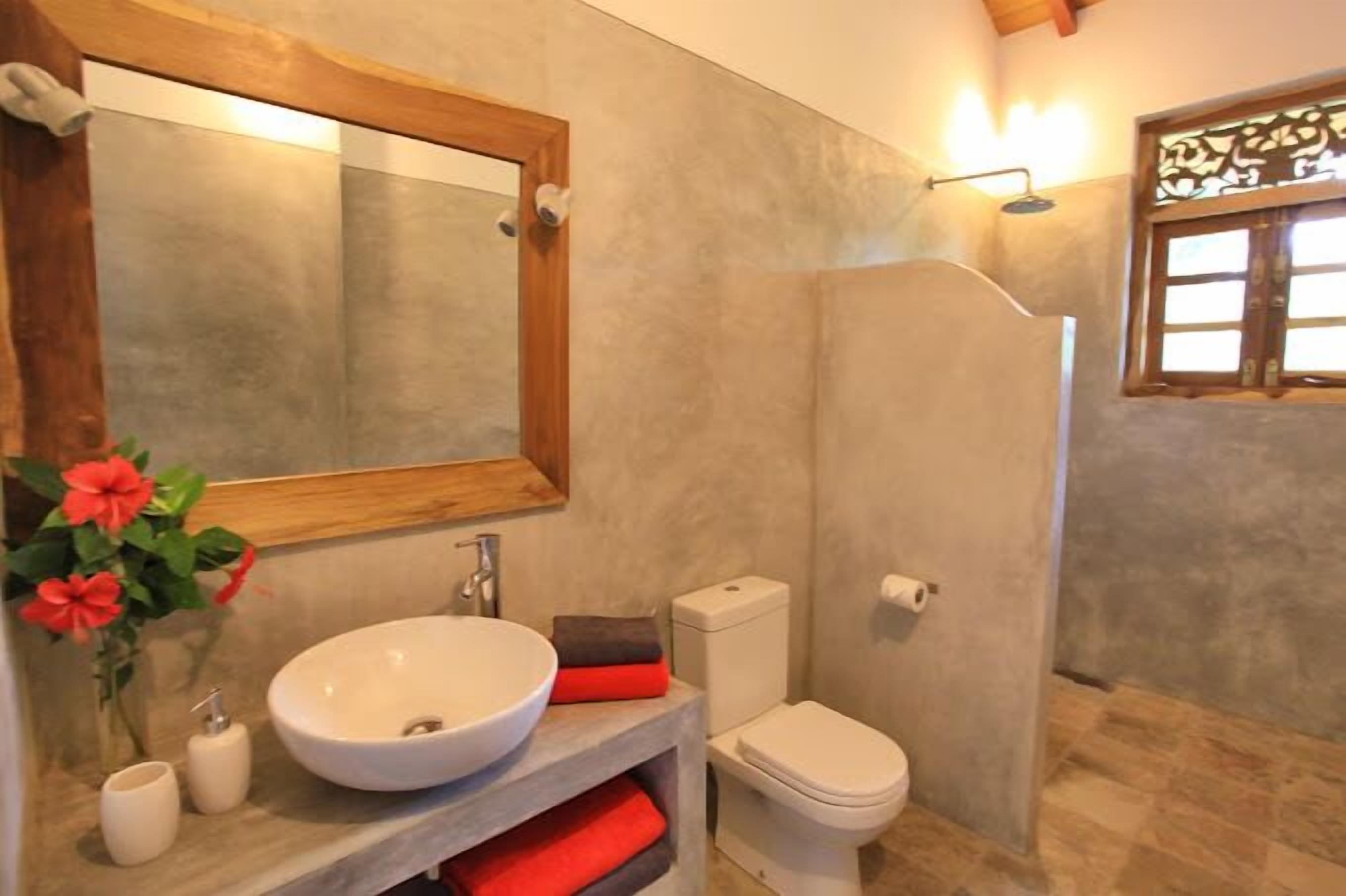 A bathroom with a large mirror, a sink, a toilet, and a shower.