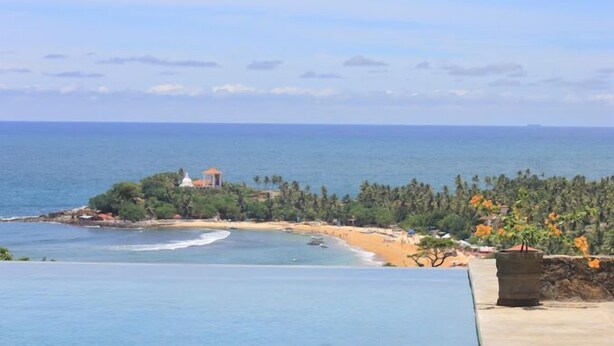 A coastal view with a beach, a small island with a white building, and a clear sky. - Far Horizons Villa by Angel (Unawatuna)