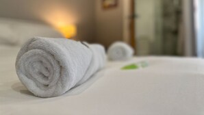 A neatly rolled white towel on a bed with a white bedspread. - Modern Room with Private Outdoor space - Pass the Keys (Newcastle)
