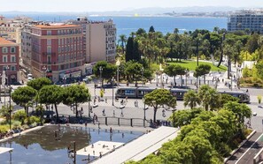 A public square with a fountain, palm trees, and a view of the sea. - Studio Neuf au Cœur du Carré Dor, rue Dalpozzo, 5 Minutes des Plages (NICE)