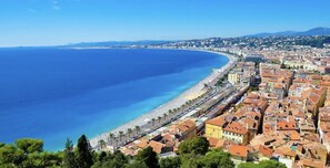 A coastal city with a long beachfront, dense urban area with traditional architecture, and a clear blue sea.