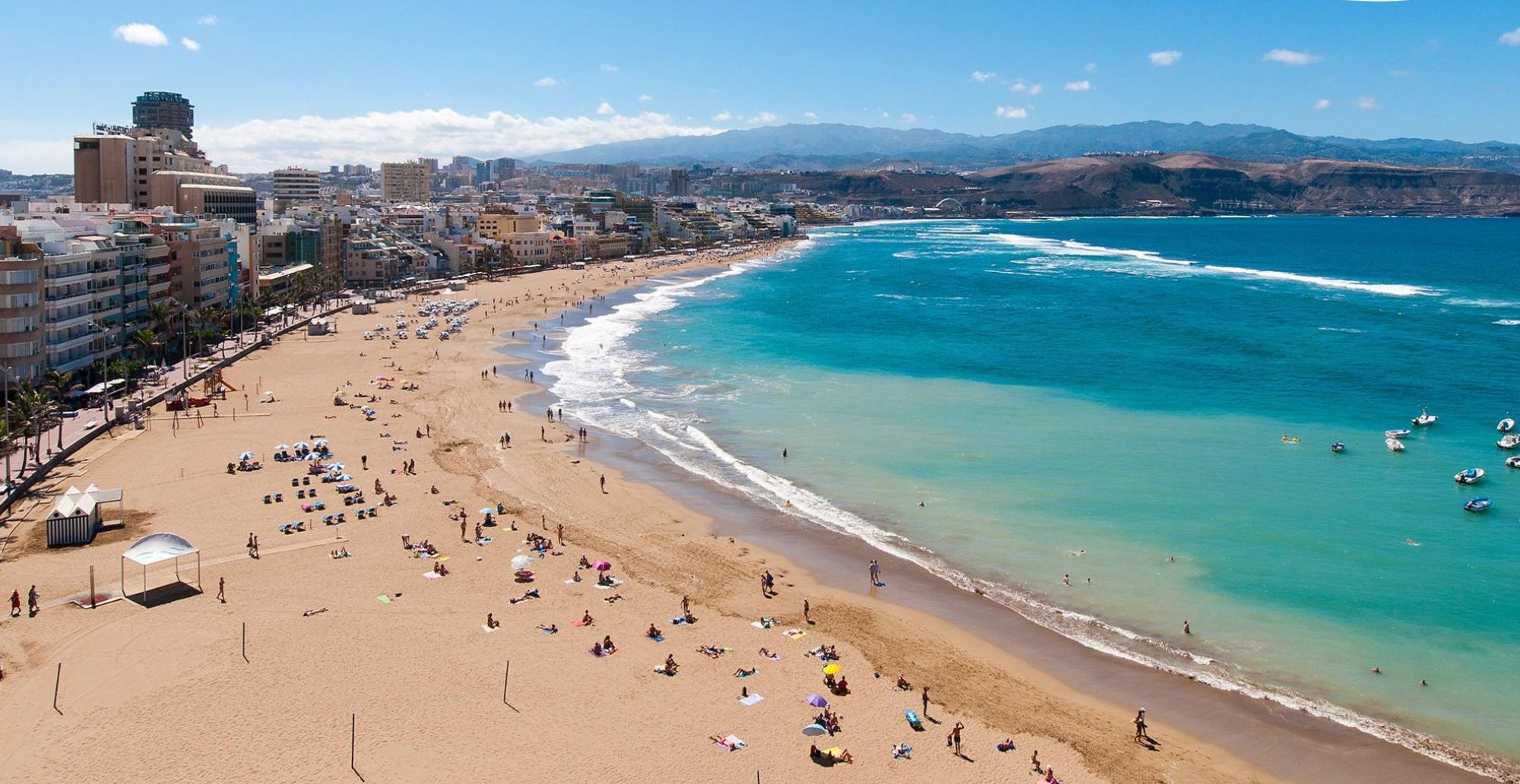Escena de playa con cielo despejado, un cartel que indica 'Las Canteras 45 min' y un icono de coche rojo.