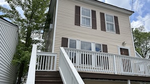 A two-story house with a white front porch and a set of stairs leading to the entrance. - Cozy 3BR Beach House by the Sea (Old Orchard Beach)