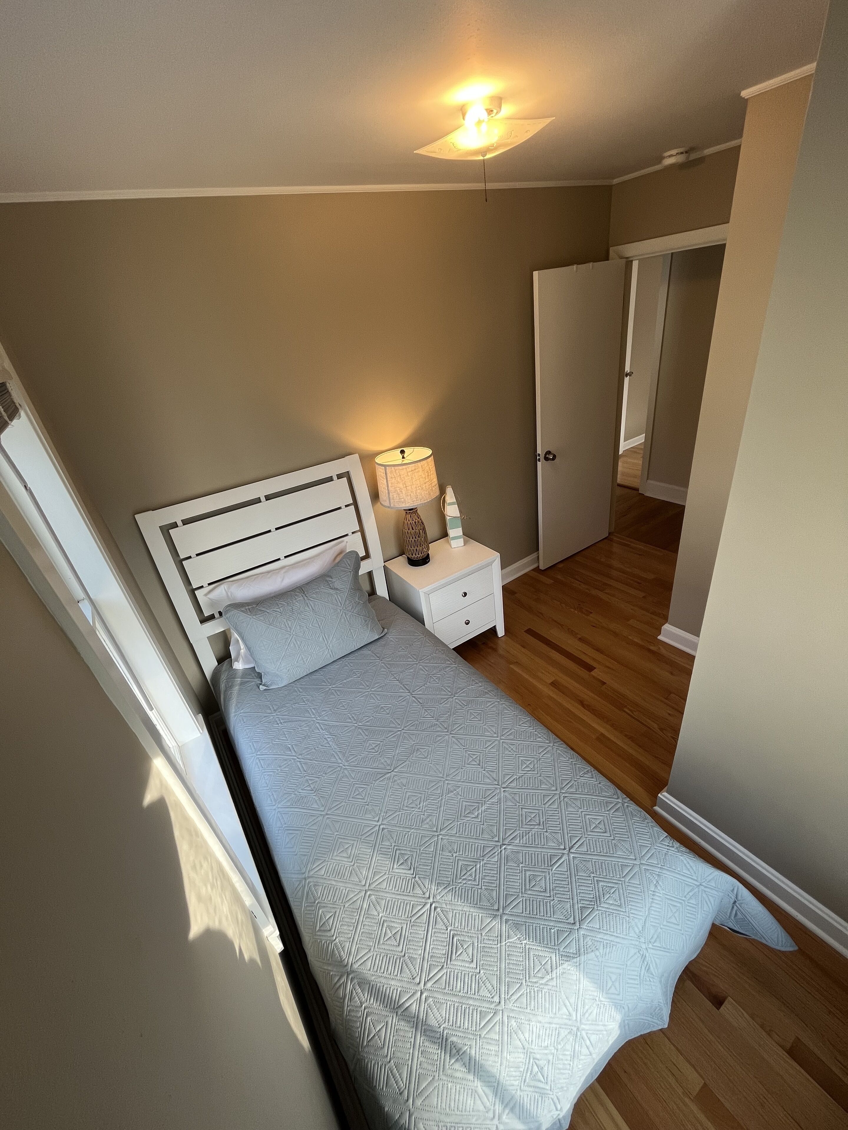 Une chambre à coucher avec un lit, une table de chevet, une lampe et un luminaire au plafond.