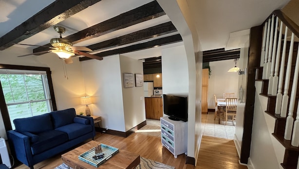 A modern living room with a blue sofa, wooden coffee table, and a ceiling fan. - Cozy 3BR Beach House by the Sea (Old Orchard Beach)