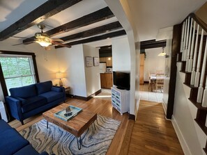 A modern living room with a blue sofa, wooden coffee table, and a ceiling fan. - Cozy 3BR Beach House by the Sea (Old Orchard Beach)