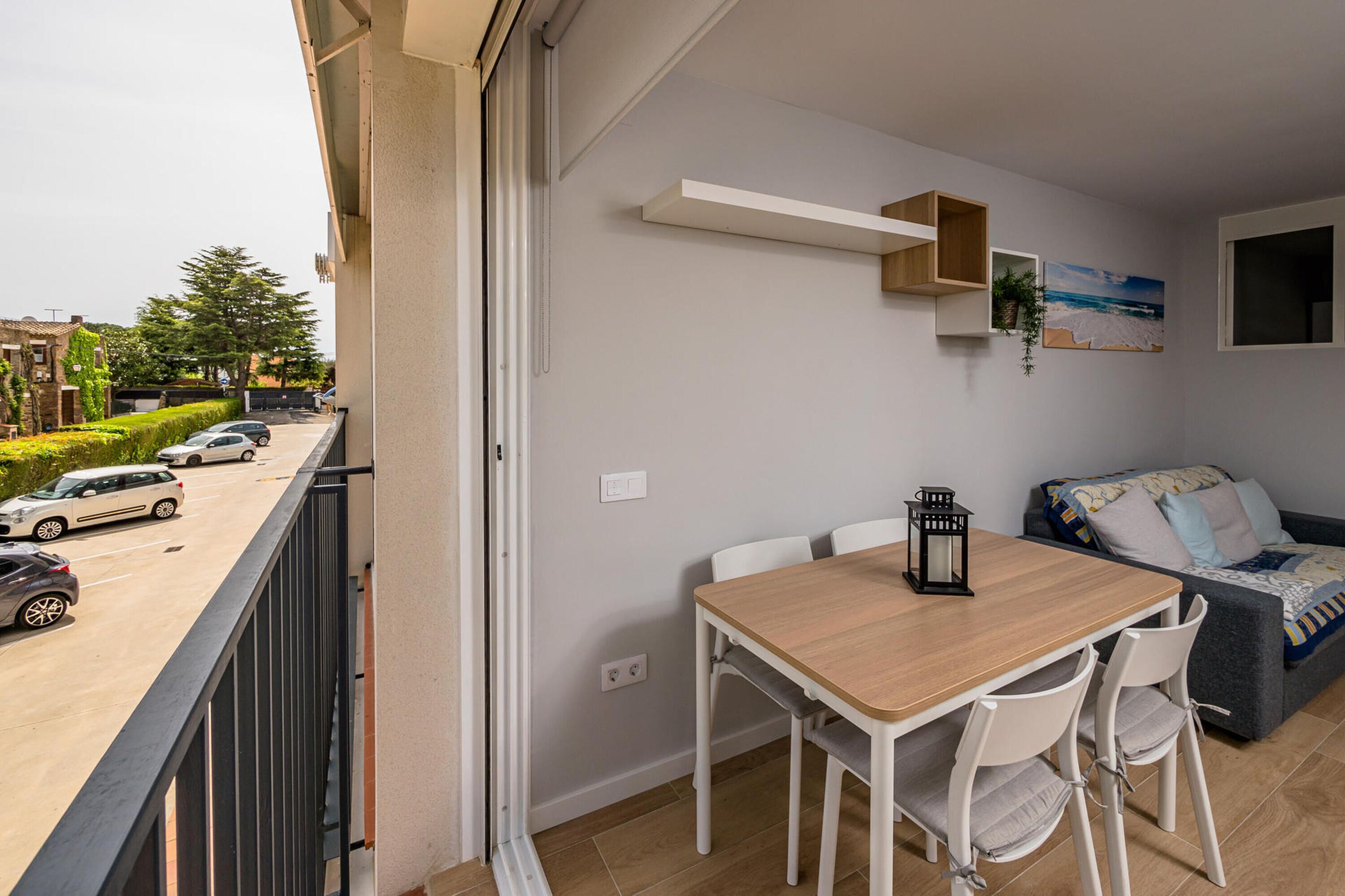 Un balcón con mesa y sillas de comedor, un sofá y una estantería en la pared.