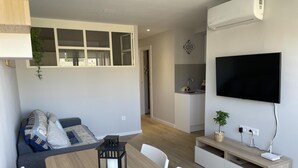 Un salon moderne avec une table à manger, un canapé et un téléviseur.
