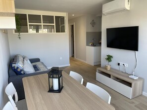 A modern living room with a dining table, sofa, and TV.