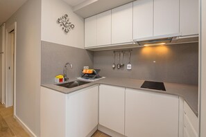 A modern kitchen with white cabinets, a stainless steel sink, and a built-in oven.