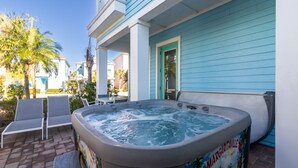 Een bubbelbad met een muurschildering, buitenmeubilair en een huis met blauwe bekleding.