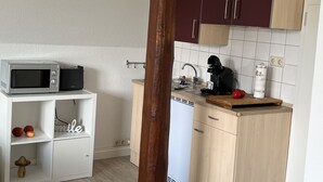 A compact kitchen with a microwave, coffee maker, and a small countertop. - Marketplace apartment (Höxter)
