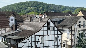 A traditional half-timbered building with a steeply pitched roof, surrounded by other similar structures. - Marketplace apartment (Höxter)