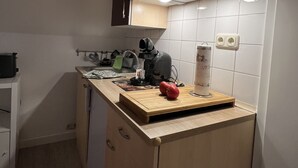 A compact kitchen with a wooden countertop, a kettle, a cutting board with a red bell pepper, and a paper towel holder. - Marketplace apartment (Höxter)