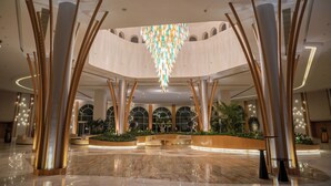 A spacious lobby with a high ceiling, a central chandelier, and a seating area with a planter. - Cleopatra Sidi Heneish (Marsa Matrouh)