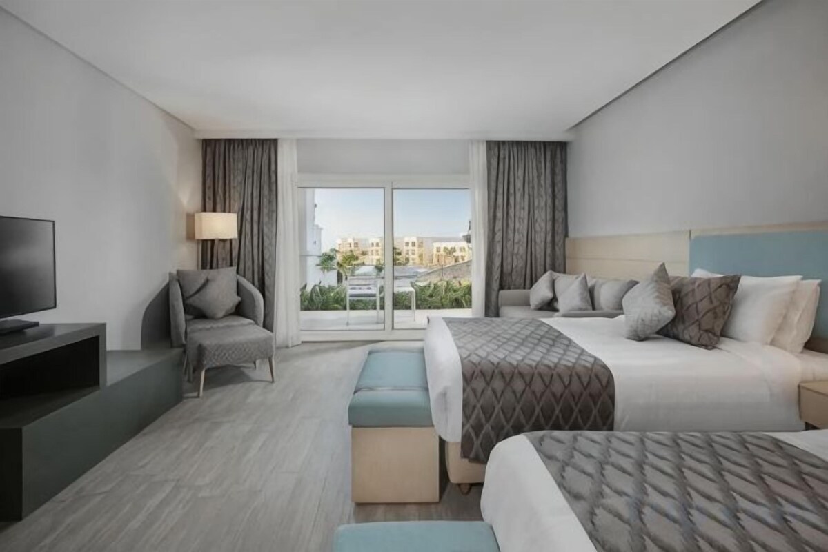 Habitación de hotel con cama, televisión, escritorio y vistas a la ciudad.