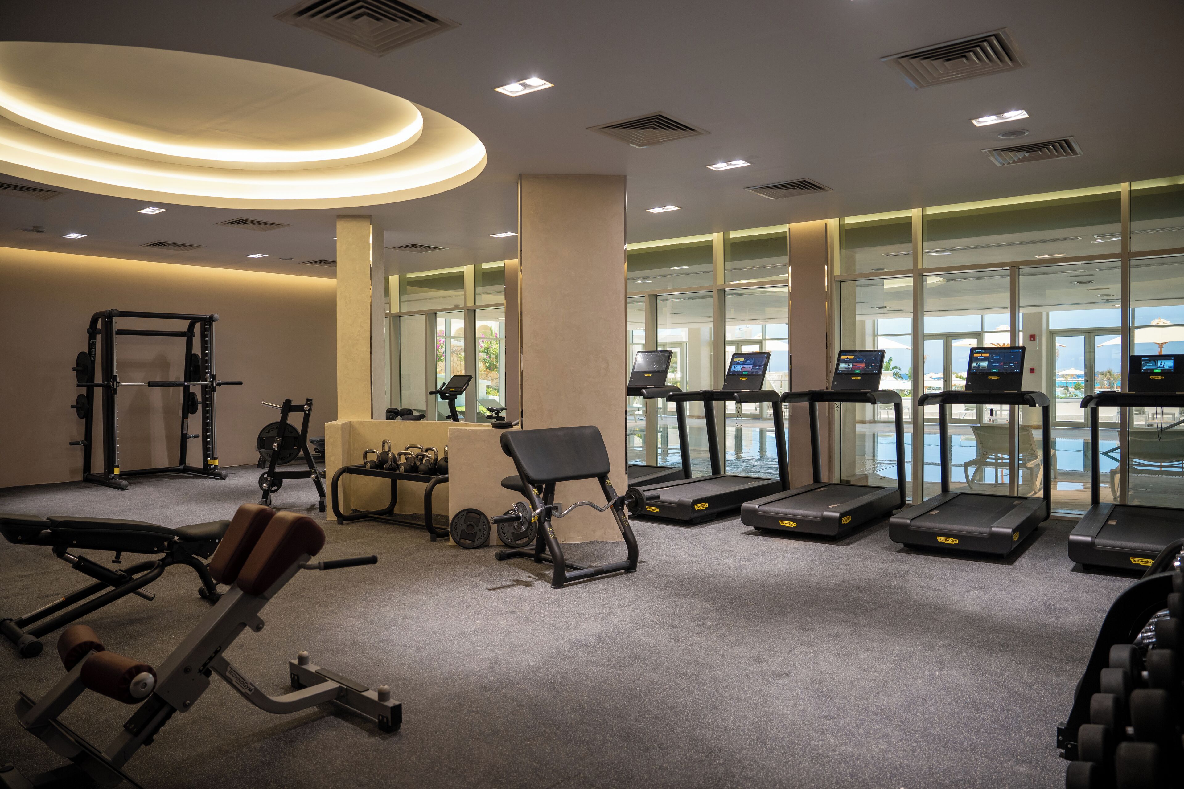 A modern gym with cardio equipment, weight machines, and a bench press.