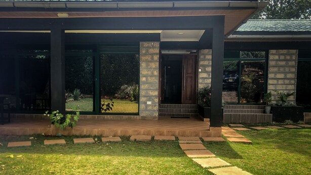 Een modern huis met een overdekte veranda, een stenen gevel en een verzorgd gazon.