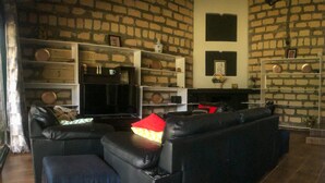 Een woonkamer met een zwarte leren bank, een flatscreen televisie en een bakstenen muur.