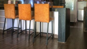 Een moderne keuken met donkere houten kasten, een centraal eiland met barkrukken, en hanglampen.