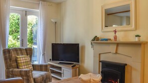 A living room with a fireplace, a television, a sofa, and a table with a decorative bowl. - 2 bedroom accommodation in Cark, near Grange-over-Sands (Cark, near Grange-over-Sands)