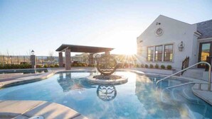 A swimming pool with a sun sculpture, a covered seating area, and a building with large windows. - Casa Blanca luxury Villa Private pool sleeps 30! (Hurricane)